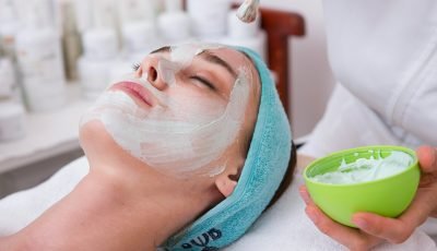 woman lying on blue towel with white cream on face